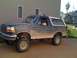 1992 Ford Bronco - Mud-covered 1992 Ford Bronco with lifted suspension and roof lights parked in a driveway.