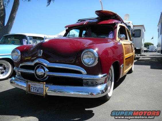 Red woody wagon with wood paneling, surfboard on roof rack, and California license plate FYRWOD