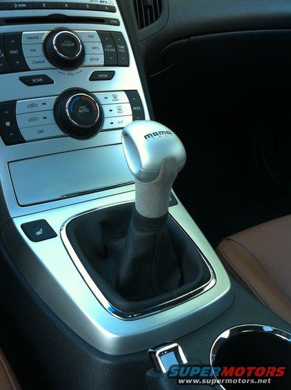 Interior view of a car's center console showing climate controls and a silver MOMO shift knob
