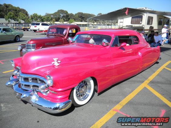Pink custom car with chrome grille and whitewall tires
