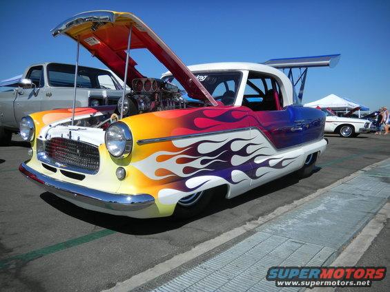Custom hot rod with flame paint, exposed engine, and large rear spoiler