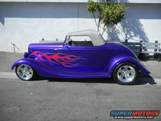 Purple hot rod with red flame decals on the side, gray convertible top, chrome wheels