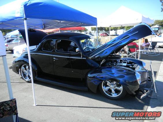 Black coupe with blue flame graphics and chrome wheels, hood open