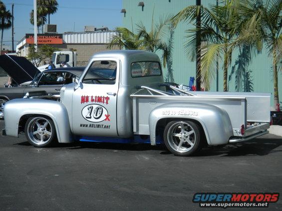 Silver pickup truck with custom wheels and roll cage, side view. "NO LIMIT 10x" and "www.nolimit.net" decals on door
