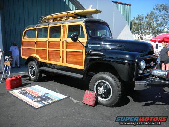 Black International Harvester woodie wagon with surfboard on roof rack