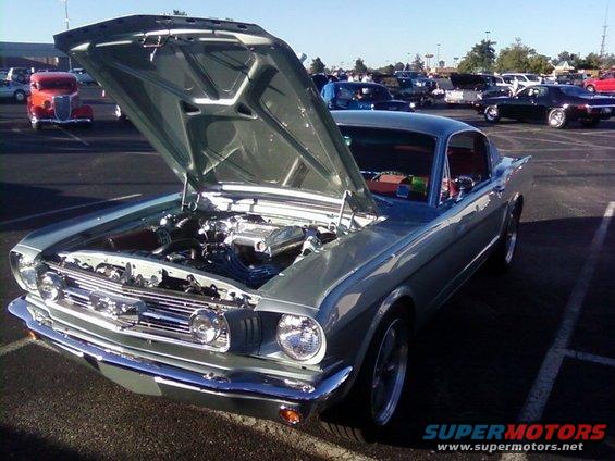 1965 Ford Mustang coupe with hood open, showing engine. Other cars in background