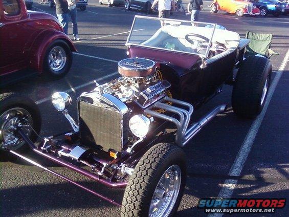 Front view of a hot rod with exposed engine and large rear tires