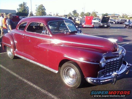 Red coupe car with chrome trim and grille, parked in a lot