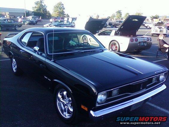 Black muscle car with chrome wheels and a silver stripe on the side. Dice hang from the rearview mirror