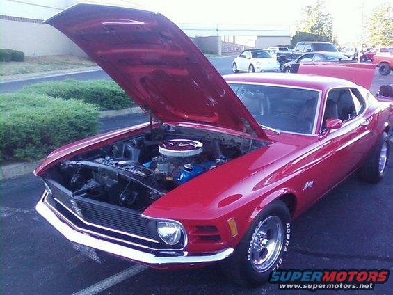 Red 1970s Ford Mustang with hood open, showing engine