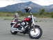 1994 Ford Bronco - Motorcycle parked with a helmet on the handlebars and mountains behind it.