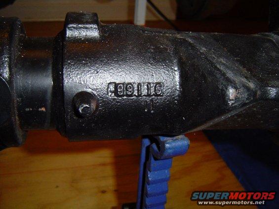 Close-up of a black metal axle housing with the numbers 499116 cast into it. It's resting on a blue jack stand