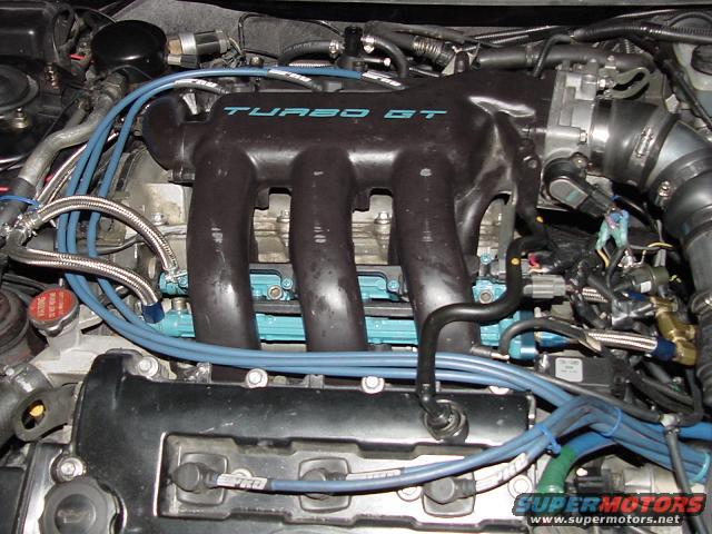 Engine bay with "TURBO GT" intake manifold, blue spark plug wires, and various hoses