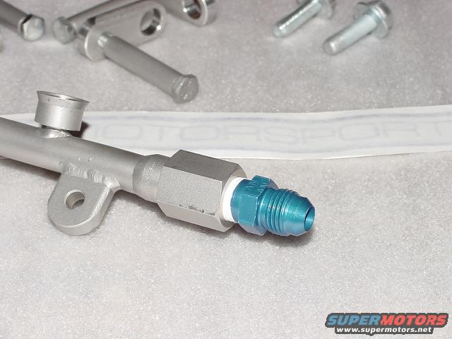 Aluminum fuel rail with blue AN fitting and several bolts in the background