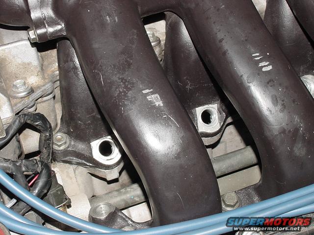 Close-up of dark-colored engine intake manifold pipes with some white markings