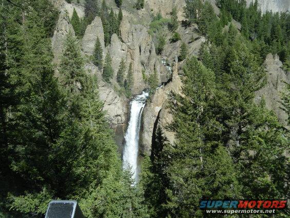 Waterfall cascading down rocky cliffs surrounded by pine trees