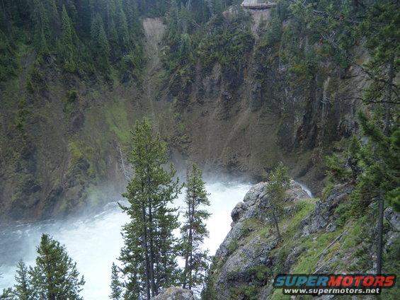 Waterfall cascading into a river in a forested canyon