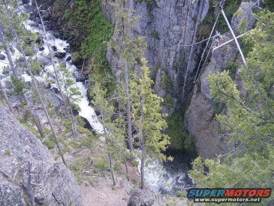 Waterfall cascading down rocks in a canyon with pine trees