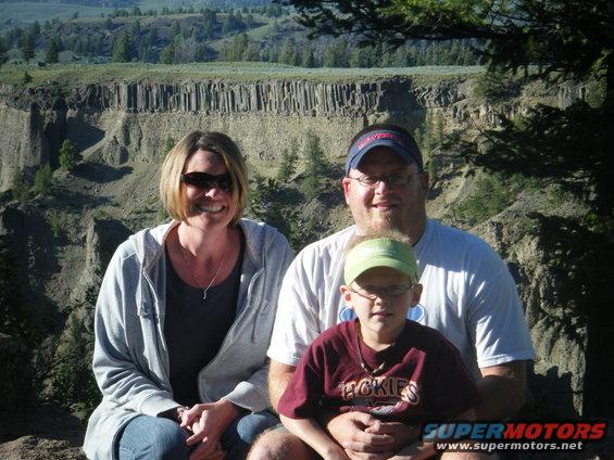 Family poses for a photo in front of a scenic canyon with columnar rock formations