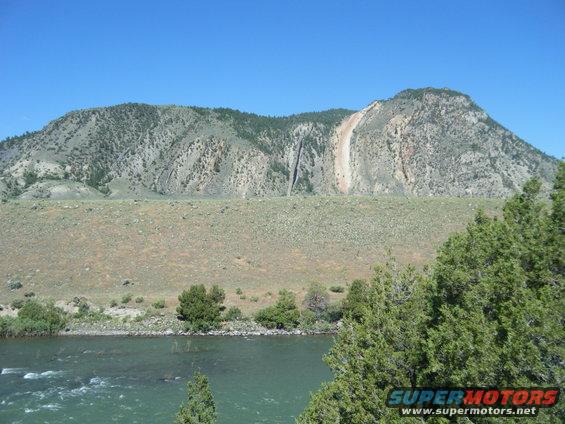 Mountain landscape with river and trees, Supermotors.net logo visible