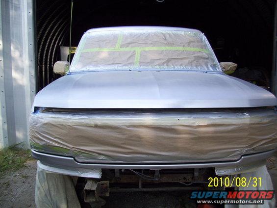Front view of a 1993 Ford Bronco prepped for paint, with masking tape on windows and front end