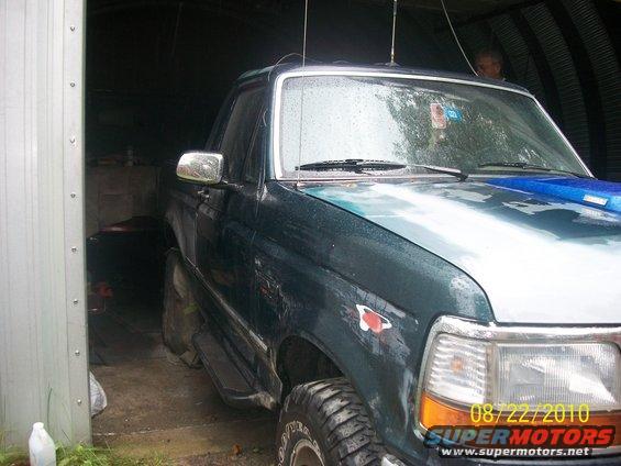 Green Ford F-Series truck in a garage. Has a blue hood accent