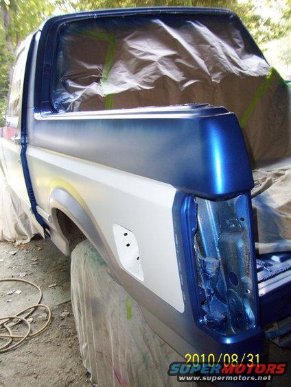 Truck bed corner and cab are covered in plastic and tape, ready for paint. The rear light is removed