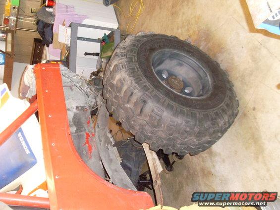 Orange fender and large tire of a Jeep CJ. Honda decal visible on blue plastic