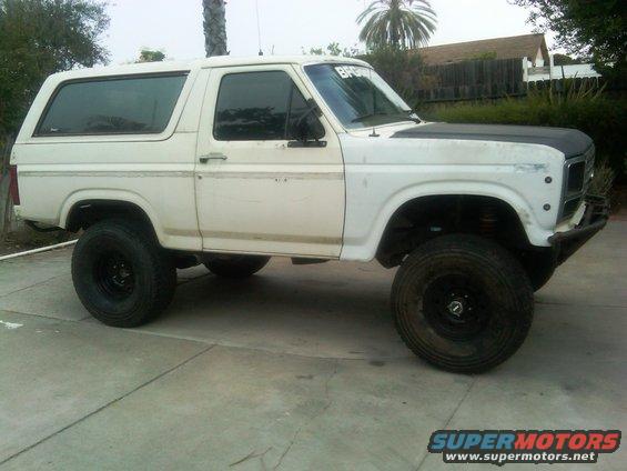 White SUV with black hood and large tires parked on a concrete surface