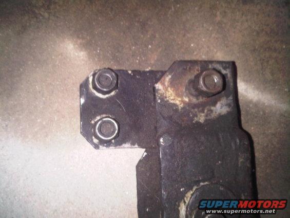 Close-up of a rusted metal bracket with two bolts on the left and one on the right