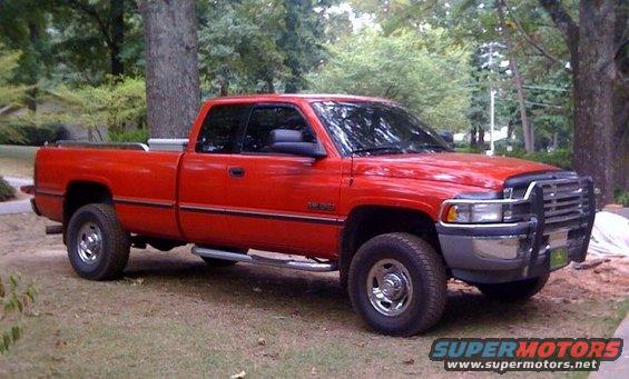 Red pickup truck parked on grass with trees in background