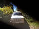 1992 Ford Bronco - A white Ford Econoline van is seen from the front on a dirt road surrounded by trees.
