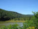 1992 Ford Bronco - A landscape a calm lake surrounded by lush green hills and trees under a bright blue sky.