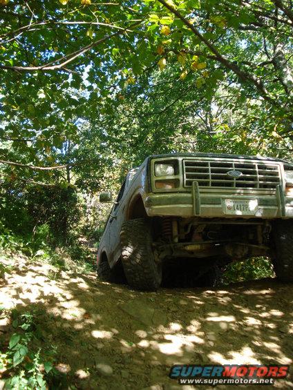 Front view of a 1980 Ford Bronco off-roading on a dirt trail