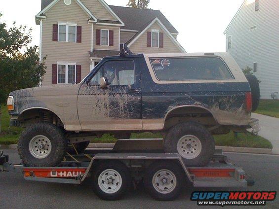 Mud-covered 1992 Ford Bronco on a U-Haul trailer, side view