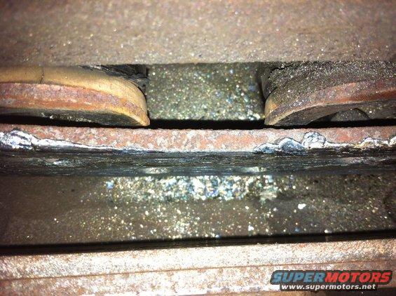worn brake pads and rotor with debris