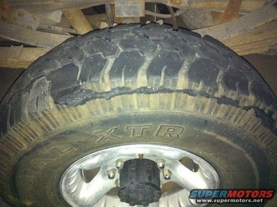 Close-up of a damaged tire with visible tread separation and a Supermotors.net watermark