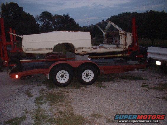 Car body being transported on a red trailer