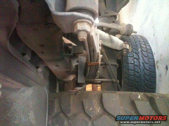 Underside view of vehicle suspension with leaf springs and tire