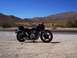 1999 Ford Crown Victoria - A motorcycle is parked on the side of a desert road under a clear blue sky.