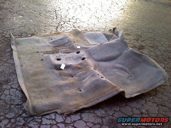 Carpet removed from vehicle, showing molded shape and mounting holes