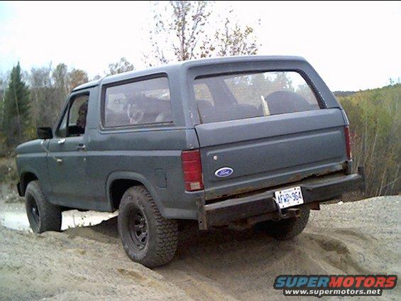 Dark gray Ford Bronco driving off-road, rear view. License plate AFVP-964