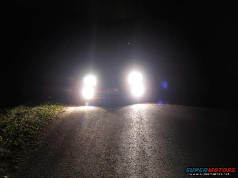 Car headlights shining on a dark road at night