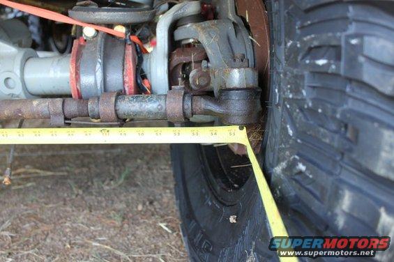 Close-up of vehicle suspension with a yellow measuring tape near the tire