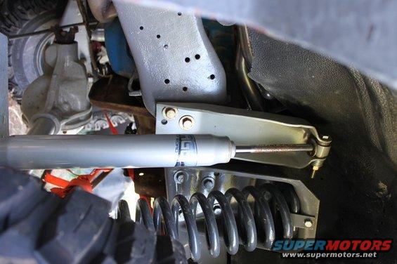Close-up of a silver shock absorber and coil spring assembly with visible text on the shock
