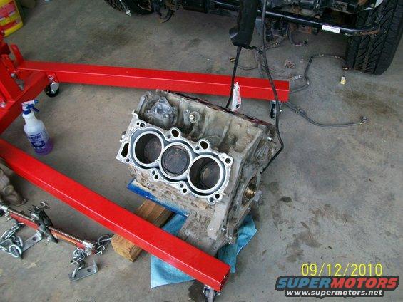 engine block on red engine stand, with spray bottle and chains nearby