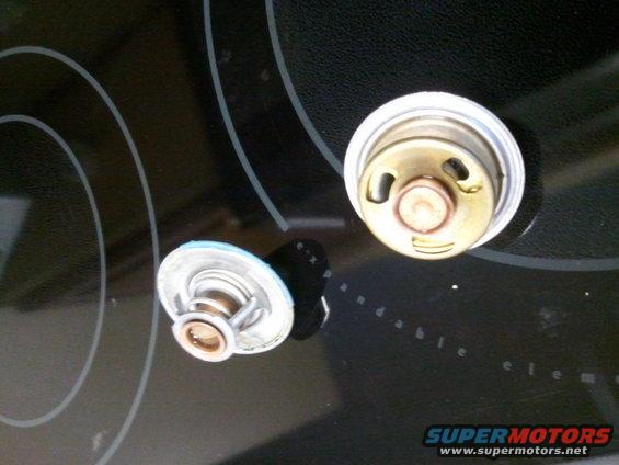 Two car thermostats on a black surface with concentric circles