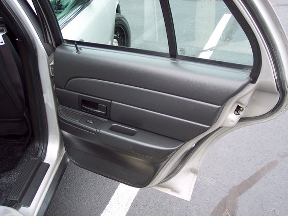Interior door panel of a silver car, with another car visible through the window