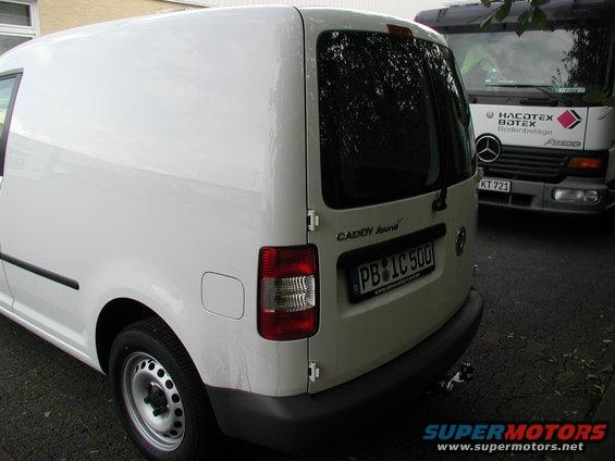 Rear view of a white Volkswagen Caddy van with a truck behind it