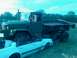 1990 Ford Bronco - A military dump truck is parked next to a white sedan in an outdoor setting.